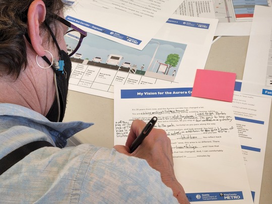 A community member writing notes on an SDOT handout, sharing their vision for the future of Aurora Ave N