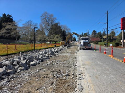 A photo showing an excavator demolishing pavement on SW Barton St.