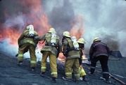 Color photo of firefighters battling a fire on the roof of a house