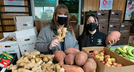Two people holding up food at a food bank