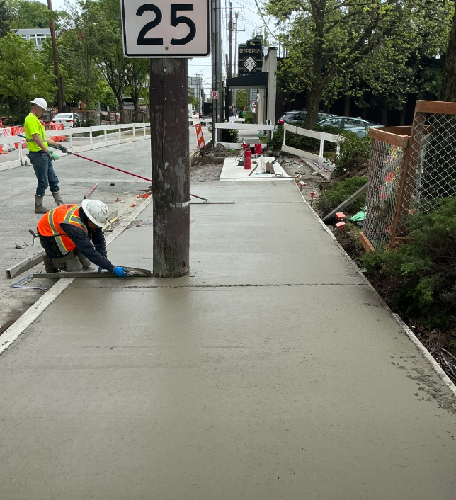 Crews smooth out new sidewalk concrete near Imperia Lake Union. 