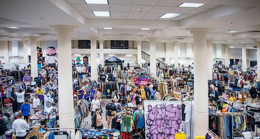 Racks with vintage clothing and people shopping
