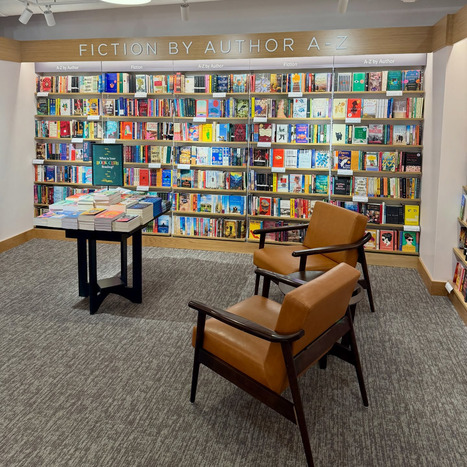 A bookshelf full of books with two chairs nearby