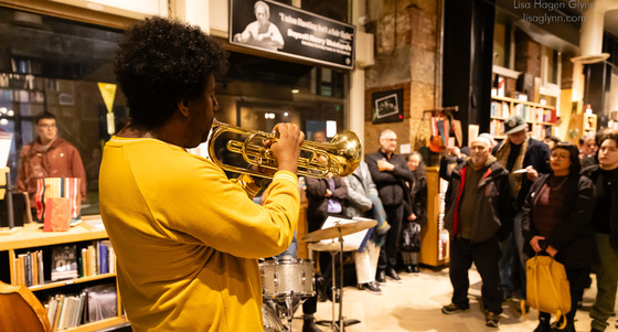 A person playing the trumpet in front of a small crowd