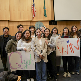A group of people standing in Seattle Council Chambers with two signs that say Quynh for the Win