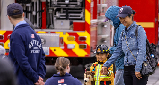 A small child with a parent meeting Seattle Fire Department firefighters