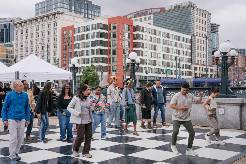 An instructor leads a crowd in dance steps on the plaza