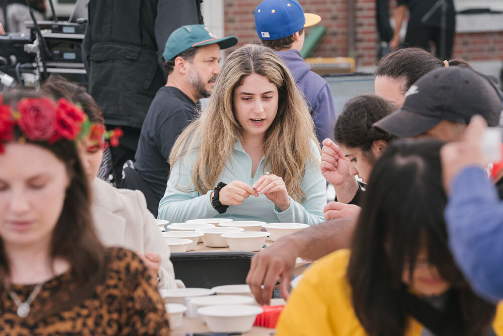 People sit down at tables full of supplies to make art
