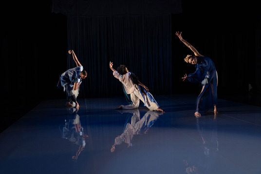 Three Black dancers in various poses with one arm gracefully extended.