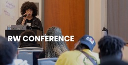 Photo of a woman at a podium talking to crowd of people. RCW is initialed in the photo.