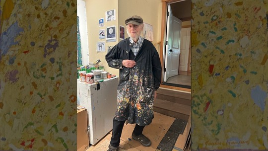 Painter Gayle Hansen poses for a photo in his painting apron