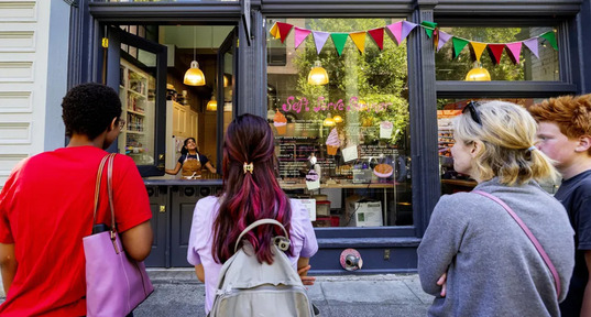 A person open the shop’s soft serve window to a waiting line