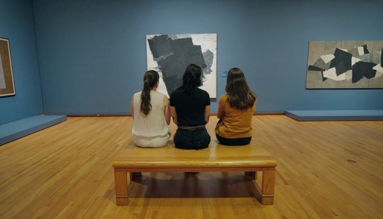 A picture of three women sitting inside the Seattle Art Museum.