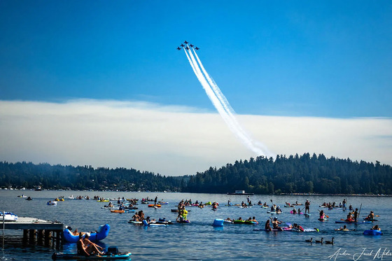 People paddle boarding on a lake with Blue Angels flying in the background