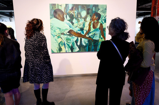 People gathered around a painting of Black people dancing at a party.