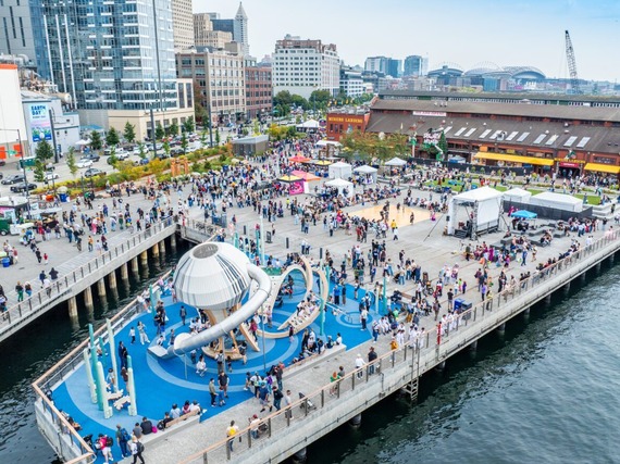 Overhead of Seattle waterfront with crowds and people playing on a large playground.