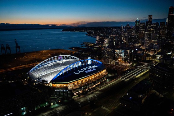 An overhead photo of Lumen Field at night with the Seattle skyline in the background.