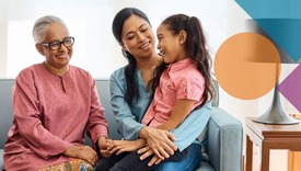 Photo a family of a grandmother and mother sitting on a couch and smiling at the granddaughter sitting on her mothers lap.