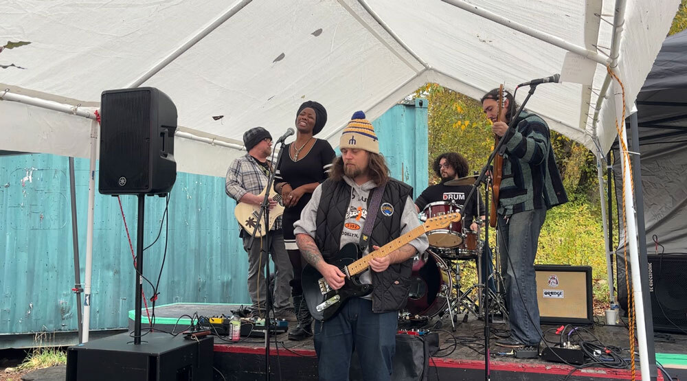 A band performs underneath a tent in the park