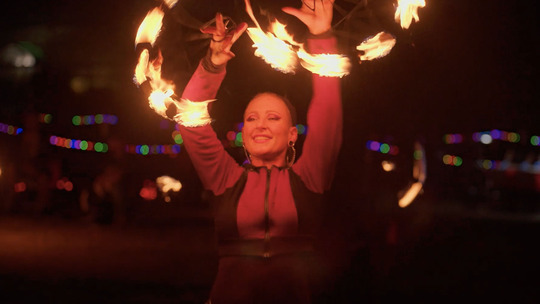 A woman twirls fire over her head.