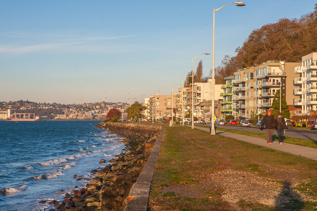 Waterfront view as the sun sets overlooking Puget sound and walkways and bike paths along Beach Drive in Seattle's Alki Beach neighborhood