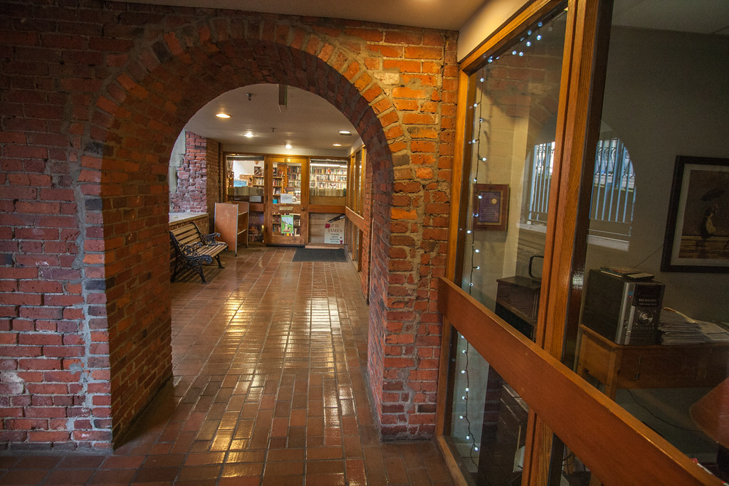 A brick arch looks onward down a brick hallway lined with glass windows in a building in Seattle