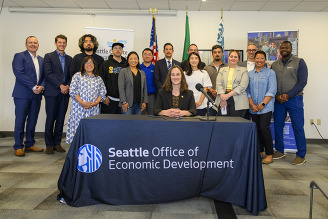 Large group smiling behind Mayor at press event