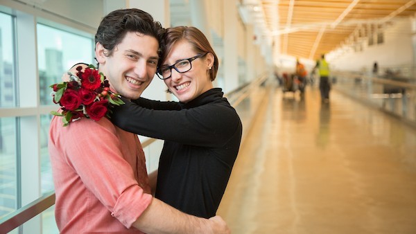 Couple embrace at a SEA Airport gate as part of the SEA Visitors Pass program