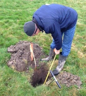 Person leaning over a hole in the ground that leads to a septic system.