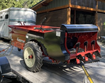 Large red manure spreader on trailer back.