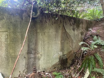 A cracked dam wall with a pipe at the top.
