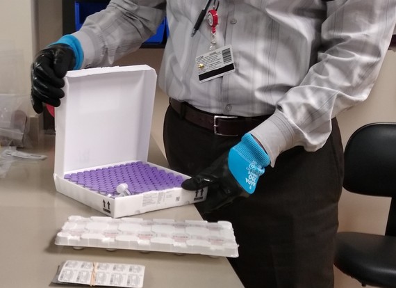 Dr. Eric Werttemberger, Pharmacy Director at Providence Regional Medical Center Everett, opens a box containing the Pfizer BioNTech COVID-19 vaccine