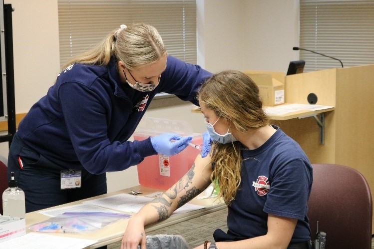 Photo of Marysville Fire District Firefighter Hayley Peterson administering COVID vaccine to Firefighter Cydney Hallahan