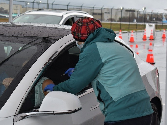 A COVID-19 vaccine is administered through a car window at the Snohomish Health District drive through vaccination site at Paine Field on  1-12-2021