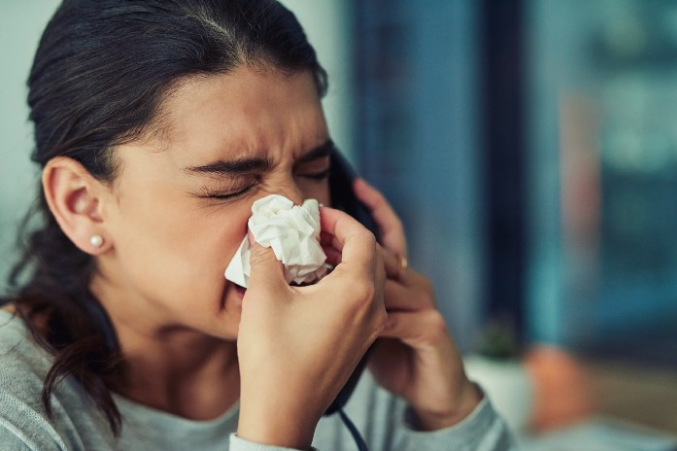Woman using tissue to blow nose