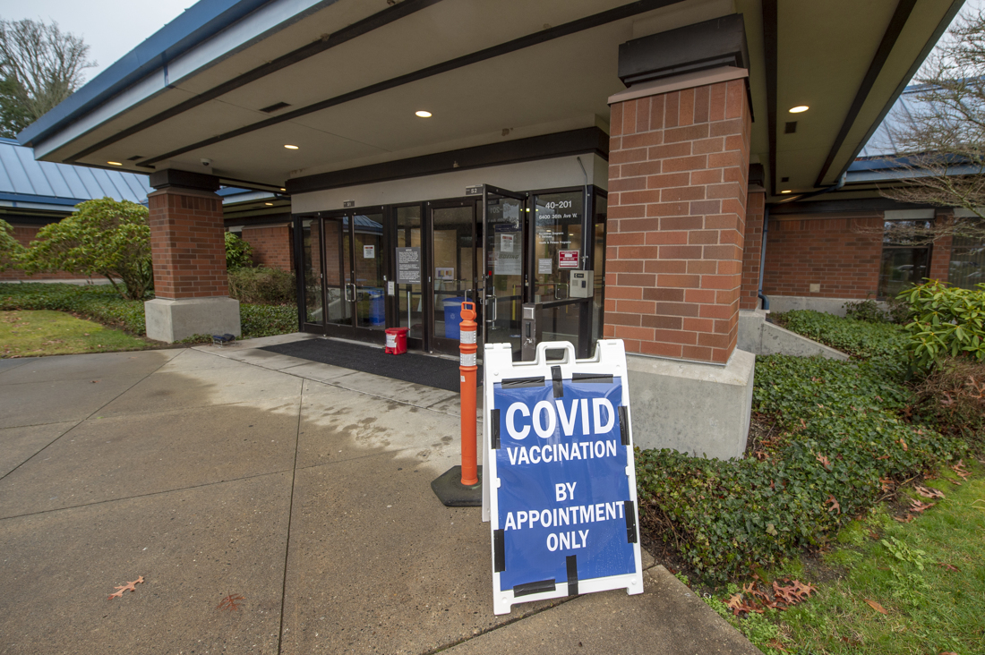 Brick building with door open and sign out front advertising COVID-19 vaccinations by appointment only