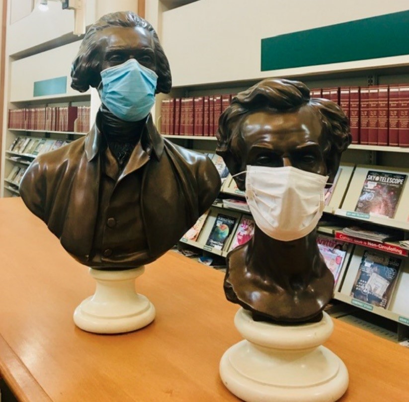 Masked busts of George Washington and Abraham Lincoln in a library