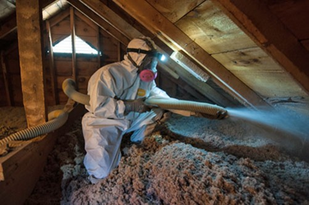 A weatherization technician sprays insulation foam into an attic.