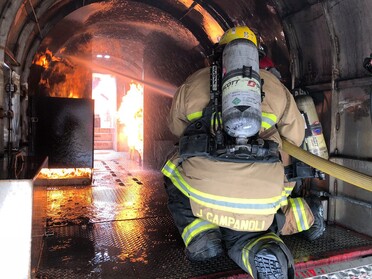 Firefighters extinguishing a fire inside of a simulated aircraft fuselage