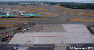 Construction equipment exposing dirt in the final phase of the Terminal Area Ramp project with an airplane in the foreground.