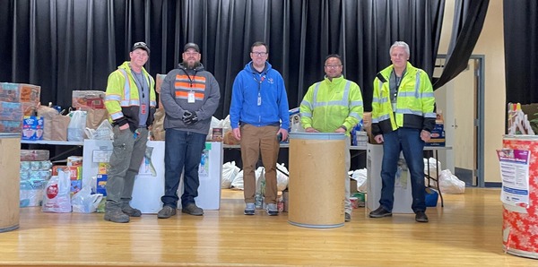 Paine Field maintenance staff display the results of the Hawthorne Elementary food drive on the school's stage.