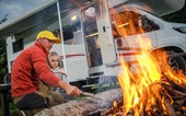 man and child outside camping with an rv in the background