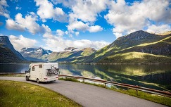 Rv going down a road with a body of water next to the road