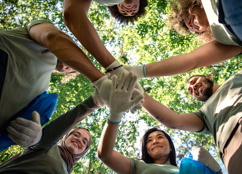 A group of volunteers with their hands together, photo taken from below their gloved hands.