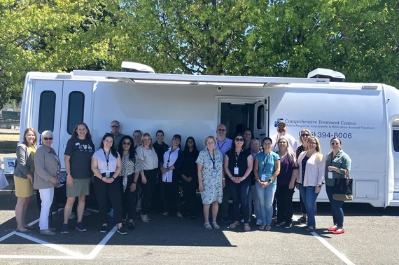 Elected officials, Human Services and Health Department staff, and clinic staff pose in front of the new mobile clinic