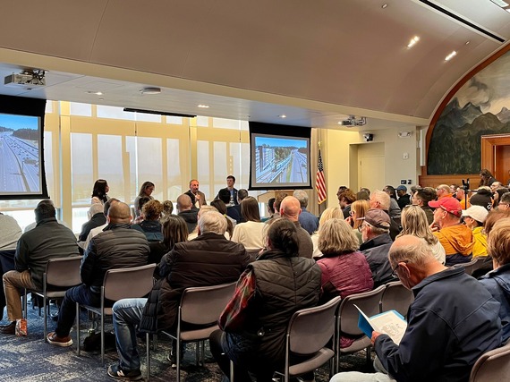 A group of people sit in the Everett Station meeting hall listening to a panel presentation