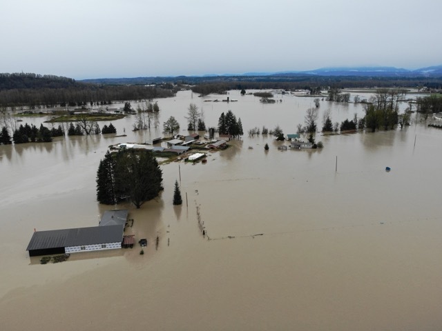 Floodwaters cover fields and parts of trees and houses during record December 2025 flood event