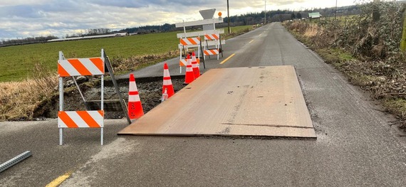 Orange traffic cones block off a large pothole in a road