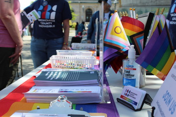 Resource fair with small Pride flags, literature, cards, various Pride swag displayed on a table from the Snohomish County Indivisible organization