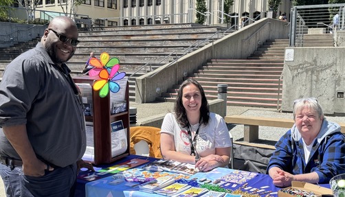 Chief DEI Officer standing next to a resource table with two female employees from Snohomish County at the Pride Resource Fair